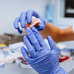 Gloved hands holding a denture