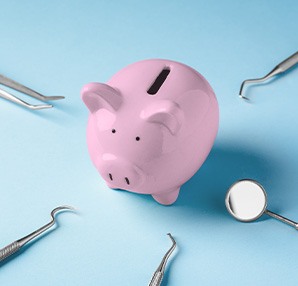 A piggy bank surrounded by dental instruments on all sides