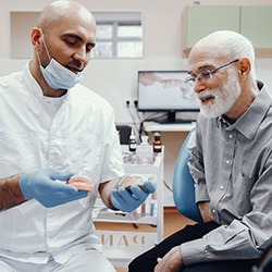 A dentist showing dentures to an older man