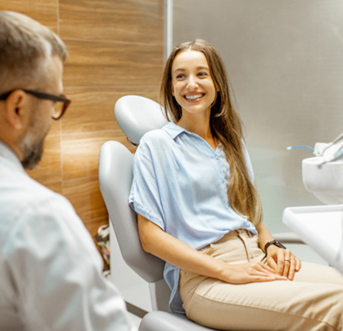 Dentist talking to smiling patient in treatment chair